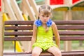 Offended five year old girl sitting on a bench at the playground