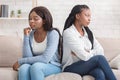 Offended girlfriends sitting back to back, ignoring each other after quarrel