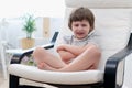 Offended little child boy sitting on couch entertaining in living room. Sad small kid enjoying free leisure time at home Royalty Free Stock Photo