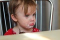 Offended little child with a dirty face is sitting in the kitchen at the table Royalty Free Stock Photo