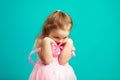 Offended little girl in pink dress on blue . Royalty Free Stock Photo