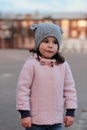 Offended little white girl walking down the street in the evening. Portrait on the background of the sunset cityscape Royalty Free Stock Photo