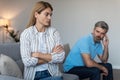 Offended mature caucasian husband ignoring wife after quarrel and thinking about divorce on sofa