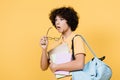 Offended schoolboy with backpack and notebooks holding eyeglasses isolated on yellow. Royalty Free Stock Photo