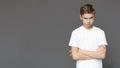 Offended teen boy standing with folded arms, panorama