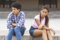 Offended teen couple sitting outdoors, ignoring each other Royalty Free Stock Photo