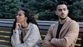 Offended young hispanic couple looking different direction sitting on bench in autumn park annoyed silent guy indignant Royalty Free Stock Photo