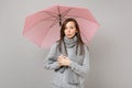 Offended young woman in gray sweater, scarf pouting lips, holding pink umbrella isolated on grey wall background Royalty Free Stock Photo