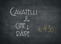 Offer of an Italian meal of Cavatelli alle cime di rapa for an amount of 4,50 euros. White words on a black chalkboard Royalty Free Stock Photo