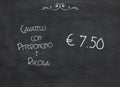 Offer of an Italian meal of Cavatelli with chilli and rocket for an amount of 7.50 euros. White words on a black chalkboard Royalty Free Stock Photo