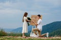 Offer in the mountains. A guy puts a ring on his bride while standing on his knee. Happy couple. Marry me. Good luck with the