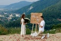 Offer in the mountains. A guy puts a ring on his bride while standing on his knee. Happy couple. Marry me. Good luck