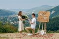 Offer in the mountains. A guy puts a ring on his bride while standing on his knee. Happy couple. Marry me. Good luck