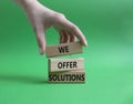 We offer solutions symbol. Concept words We offer solutions on wooden blocks. Beautiful green background. Businessman hand. Royalty Free Stock Photo