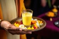 offering a glass of mango lassi to a guest