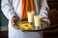 offering a glass of mango lassi to a guest