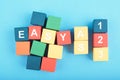EASY AS 123 word on wooden cube over blue background Royalty Free Stock Photo