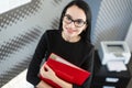 Beautiful young businesswoman in black dress and glasses hold paper folder Royalty Free Stock Photo