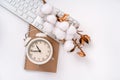 Office background with clock, keyboard and cotton branch on white Desk. Top view with space for text