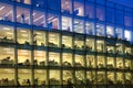 Office block with lots of lit up windows and late office workers inside. City of London business aria in dusk. Royalty Free Stock Photo