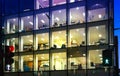 Office block with lots of lit up windows and late office workers inside. City of London business aria in dusk. Royalty Free Stock Photo