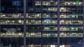 Office building exterior during late evening with interior lights on and people working inside night timelapse Royalty Free Stock Photo