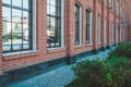 Office building in loft style. Large Windows. Red brick wall. Green bushes on the right. Perspective shot composition Royalty Free Stock Photo