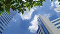 Office building and tree under white clouds and blue sky on the warmest noon in Thailand