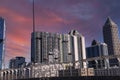 An office building under construction with workers and sliding platforms along the building surrounded by other glass skyscrapers