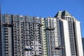 An office building under construction with workers and sliding platforms along the building surrounded by other glass skyscrapers Royalty Free Stock Photo