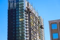 An office building under construction with workers and sliding platforms along the building surrounded by other glass skyscrapers Royalty Free Stock Photo