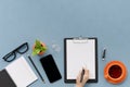 Office, business utensils on a blue table, telephone, a cup of tea, pencils, a notebook, glasses, a plant in a pot. Hand signing Royalty Free Stock Photo