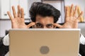 Office businessman hiding behind laptop computer making funny silly face fooling around, disrespect Royalty Free Stock Photo