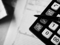 Office calculator and a pen over documents close up shot in black and white Royalty Free Stock Photo