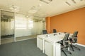 Office cubicle with white furniture, black swivel chairs, sockets on tables, gray carpet floor, plaster ceiling and glass panel as Royalty Free Stock Photo