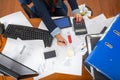 Office desk as seen from above, papers spread out, calculators, computer keyboards, pens and arm writing