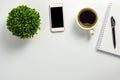 Office desk with black blank screen, coffee cup, plant pot, notebook and pen