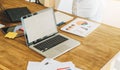 Office, desk. Close-up of a laptop on a wooden table. Nearby are paper graphics, charts, diagrams, a digital tablet Royalty Free Stock Photo