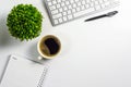 Office desk with coffee cup, blank notebook, black pen, laptop computer and plant pot