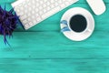 Office desk with copy space. Digital devices wireless keyboard and mouse on blue wooden table with cup of fresh coffee, top view Royalty Free Stock Photo