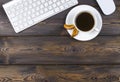 Office desk with copy space. Digital devices wireless keyboard and mouse on dark wooden table with cup of coffee, top view Royalty Free Stock Photo