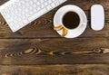 Office desk with copy space. Digital devices wireless keyboard and mouse on dark wooden table with cup of coffee, top view Royalty Free Stock Photo