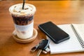 Office desk with cup of iced coffee and phone, car key on notebook Royalty Free Stock Photo