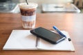 Office desk with cup of iced coffee phone on notebook Royalty Free Stock Photo