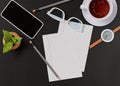 Office desk with a cup of tea, smartphone, wristwatch, notebook, pencil, glasses, potted plant. View from above. Template for Royalty Free Stock Photo