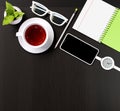 Office desk with a cup of tea, smartphone, wristwatch, notebook, pencil, plant in a pot. View from above. Template for business Royalty Free Stock Photo