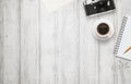 Office desk with free space for text. Camera, cup of coffee, paper, notepad, pencil on white wooden table