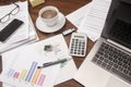 Office desk full with documents, glasses, laptop, and coffee, b