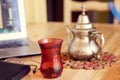 Office desk gray laptop silver arabic tea pot and notebook red cup Royalty Free Stock Photo