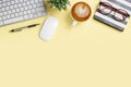 Office desk with keyboard computer, Pen, notebook, mouse, Cup of coffee on yellowbackground, Top view with copy space